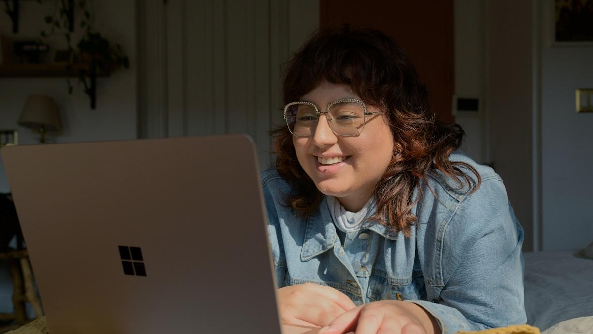 A practice owner smiling at her laptop while pulling up her clinic's numbers