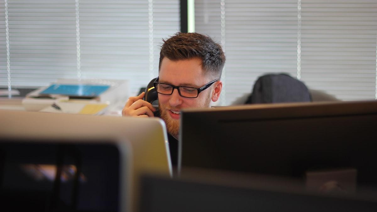 Front-desk coordinator fielding a question by phone at his computer