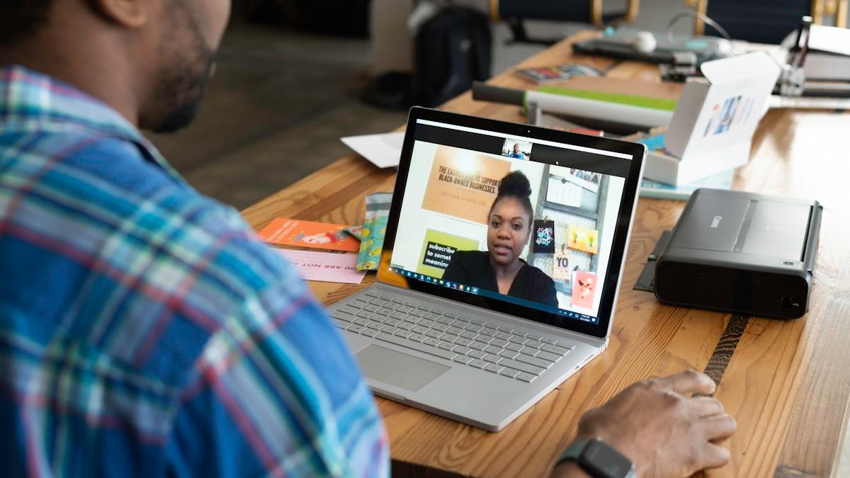 A therapist mid-conversation on a video session with a client, laptop open in her office